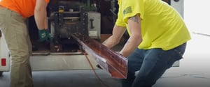 Restoration technician lifting piece of copper gutter
