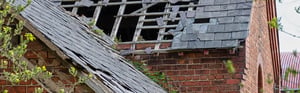 historic building with a slate roof that is severely damaged