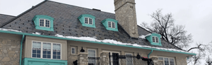 Historic home with slate roof that has snow on it.