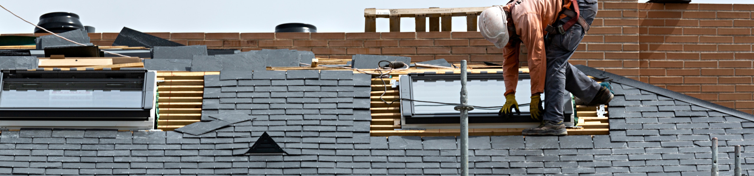 man putting a new slat tile roof on a historic home